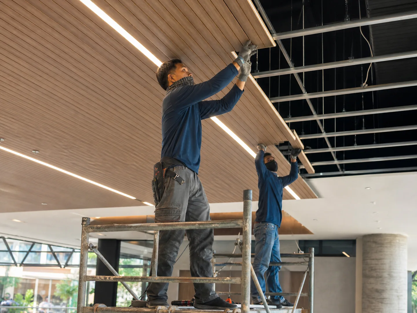 Ceiling installers fitting timber-look slats and integrated lighting